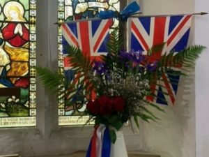 Union jack flags with flowers in front of stained glass window in the church