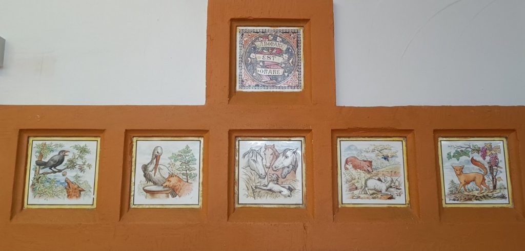 The painted tiles on the chimney-piece illustrating some of Aesop’s fables by Gibbs and Moore of London
